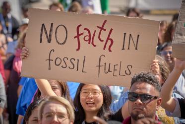 Woman holding a banner "No faith in fossil fuels"