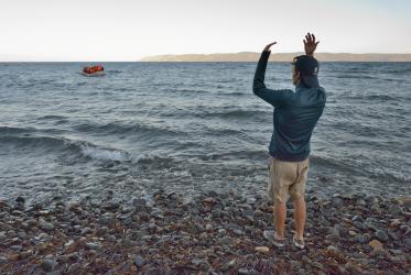 A volunteer waves a refugee boat ashore